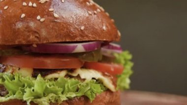 soğan, peynir, domates, salata yaprağı yakın çekim üzerinde gri bir arka plan üzerinde dana pirzola ile iştah açıcı sulu hamburger.