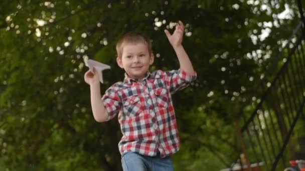 Μικρό αγόρι εγκαινιάζει ένα χάρτινο αεροπλανάκι. — Αρχείο Βίντεο