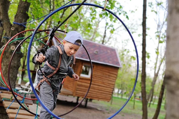 Kleine jongen op een attractie in een touw park passeert een hindernisbaan — Stockfoto