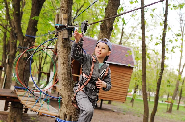 Enfant préscolaire garçon est un obstacle dans un équipement de sécurité alpinisme cours de corde haute — Photo