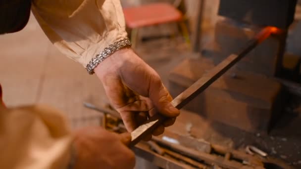 Hands of a blacksmith with a tool on the background of a forge — Stock Video