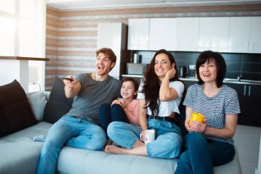 Büyük bir aile televizyon izliyor. Erkek kardeşler, kız kardeşler, anne, büyükanne ve kız torun