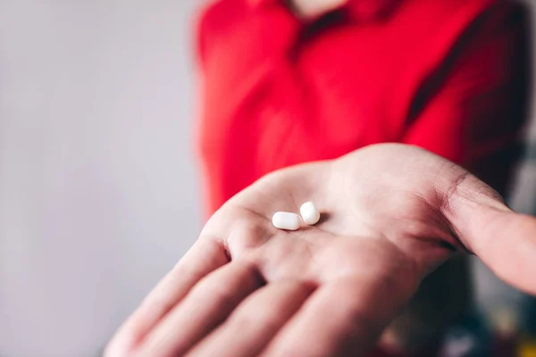 Cut view of males hand holding two sugar coated sweets. Guy in red shirt show it on camera. Tasty delicious yummy snack. — Stock Photo, Image