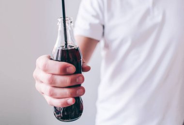 Genç adam arka planda izole edilmiş. İçinde kokain ve plastik siyah pipet olan erkeklerin el ele tutuşmalarını kesin. Tatlı, tatlı bir içecek..