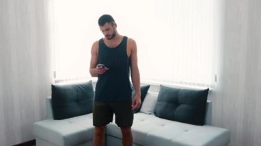 Genç adam evde egzersiz yapıyor. Yavaş çekimde kulaklıkla müzik açıp akıllı telefon kullanarak odada aynı noktada koşmaya başlıyor. Eğitimden ve egzersizden önce vücut ısıtılıyor.