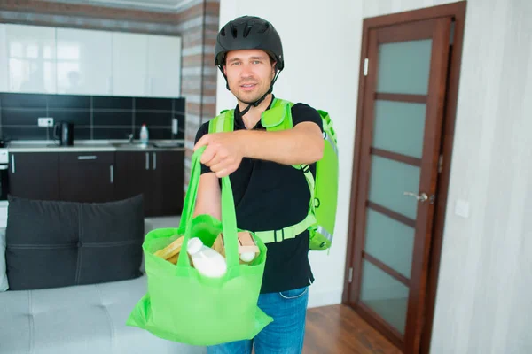Food Delivery Man Brought Food Home. he is wearing a helmet. He has a backpack - a refrigerator for food delivery.