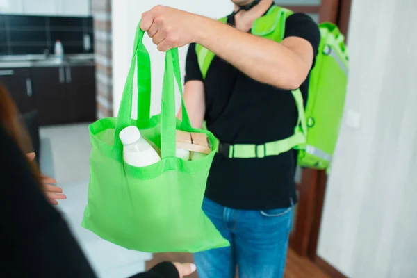 Food Delivery Man Brought Food Home. he is wearing a helmet. He has a backpack - a refrigerator for food delivery.