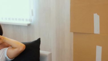 Genç çift yeni bir daireye taşınıyor. Erkek ve kadın kanepede birlikte oturup dinlenirler. Taşındıktan sonra yoruldum. Uyku zamanı..