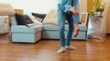 Genç çift yeni bir daireye taşınıyor. Kadını ellerinle tutup, etrafında döndüren adamın alçak görüntüsünü kes. İnsanların bacak ve ayaklarının videosu.