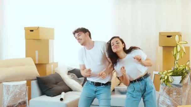 Junges Paar bezieht neue Wohnung Mann und Frau stehen zusammen und tanzen. Sie bewegen ihren Körper in die gleiche Richtung. Viel Spaß in neuer Wohnung. — Stockvideo
