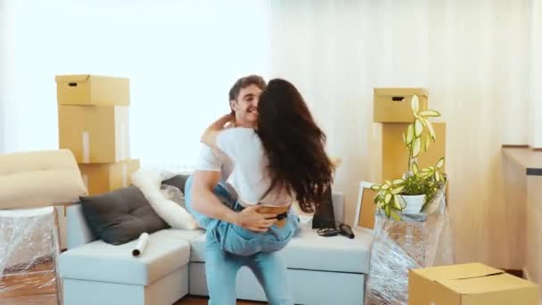 Junges Paar bezieht neue Wohnung Mädchen springen auf Jungs Hände und er beginnt sie herum zu drehen. Gemeinsam tanzen und entspannen. Glückliche Menschen in ihrer neuen Wohnung. — Stockvideo