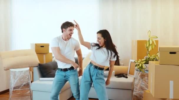 Junges Paar bezieht neue Wohnung Video von Mann und Frau, die zusammen in der Wohnung tanzen und Spaß haben. Berühren einander an den Hüften und lachen laut. Nach Umzug. — Stockvideo