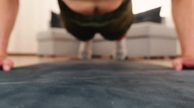 Genç adam evde egzersiz yapıyor. Erkeklerin yüzünün önünde odaklanmış bir video. Adam egzersiz yapıyor ve yerden şınav çekiyor. Yoğun egzersiz.