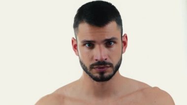 Genç adam arka planda izole edilmiş. Kamerada poz veren esmer adam. Çıplak gövdesi olan ciddi bir kendine güvenen adam. Gülümsemeye mutlulukla başlıyoruz. Kendinden emin, neşeli erkek..