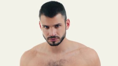 Genç adam arka planda izole edildi. Adam doğrudan kameraya bakıyor ve dudaklarıyla gülümsemeye başlıyor. Filmde çıplak gövdesi olan neşeli, pozitif adam..