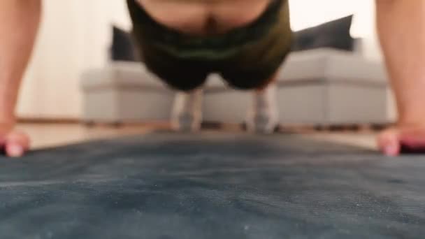 Young man exercising at home. Focused video in front view of guys face. Man exercising and doing push ups from floor. Intense exercise. — Stock Video