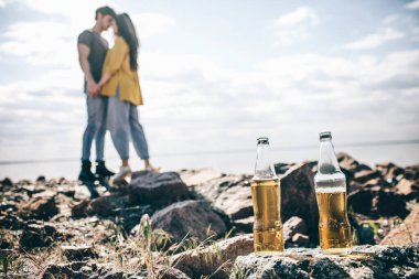 Seyahat, turizm, kadın ve erkek katlanabilir portatif bir arabada su kenarında şampanya içerler. Su kenarında piknik. Macera yaşayan bir çift. Araba yolculuğu kavramı.