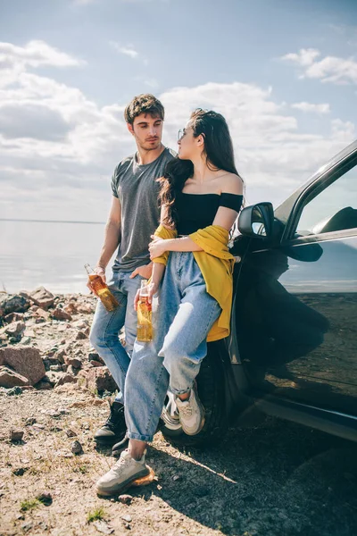 Viajes, turismo - Picnic cerca del agua. Un par de aventuras. Concepto de viaje en coche. Hombre y mujer beben cerveza — Foto de Stock