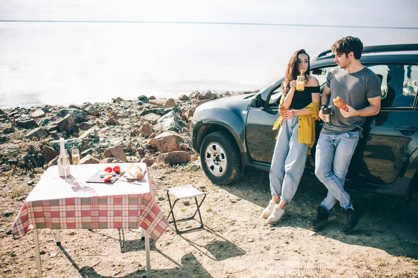 Piknik a víz mellett. Boldog család autókiránduláson. Férfiak és nők utaznak a tengeren, az óceánon vagy a folyón. Nyári utazás autóval. — Stock Fotó