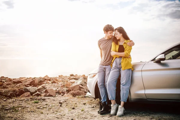 Casal atraente jovem romântico assistindo o pôr do sol e beijando com carro esportivo — Fotografia de Stock