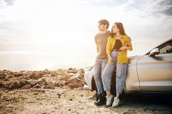 Casal atraente jovem romântico assistindo o pôr do sol e beijando com carro esportivo — Fotografia de Stock