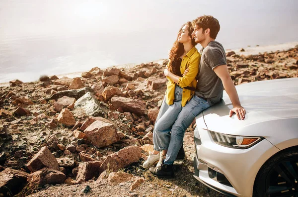 Casal atraente jovem romântico assistindo o pôr do sol e beijando com carro esportivo — Fotografia de Stock