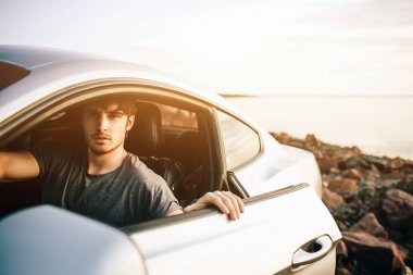 Moda gençleri arabayla seyahat ediyorlar. Yaz yolculuğunda rahat ve mutlu bir adam.