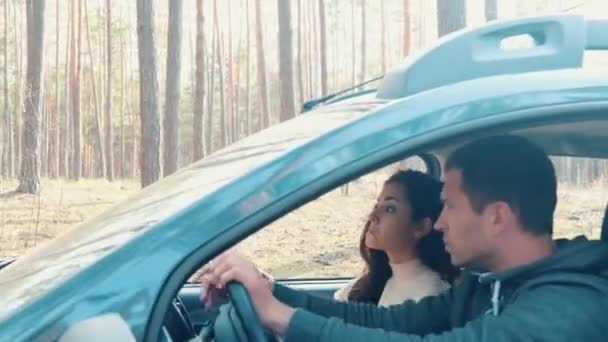 Joven hombre y mujer cabalgando juntos en coche en el bosque. Perdieron en el bosque y tratan de encontrar el camino. Pareja mira el teléfono inteligente usando el mapa en línea. Chico conduciendo coche . — Vídeo de stock