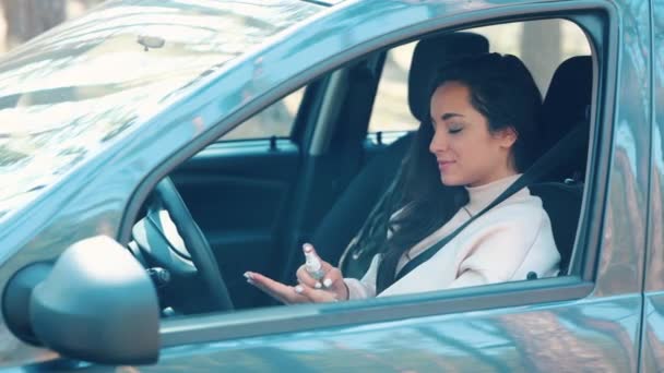 Mujer joven sentada en coche durante la pausa de viaje. Cuida de las manos y desinféctate. Usar spray para limpiar las manos. Chica en coche durante la pausa de viaje corto . — Vídeos de Stock