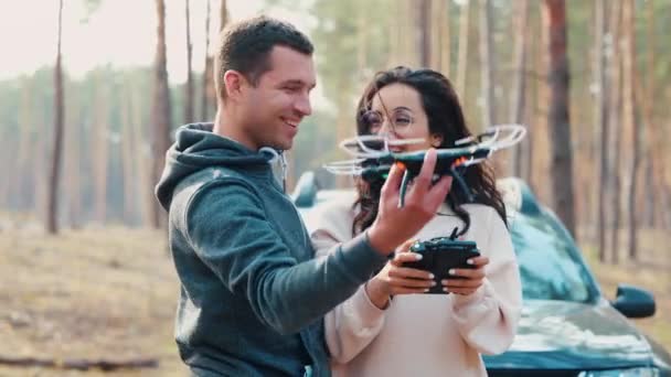 Jongeman en vrouw staan samen in het bos. Lanceer de drone. Hij moet overgeven en in de lucht kijken. Meisje houden remote cotrol voor drone control. — Stockvideo