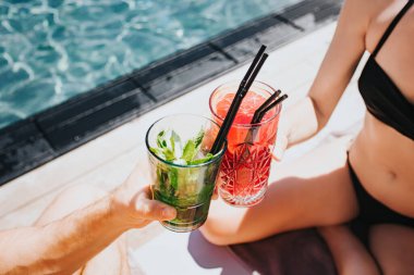 Genç ve seksi bir çift yüzme havuzunda dinleniyor. Kokteyl içen ve tezahürat yapan erkek ve kadınların ellerini kesin. Birlikte suda zaman geçirdik. Tatil sırasında dinlenmek.