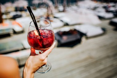 Genç seksi kadın yalnız dinleniyor. Buz küplü kırmızı soğuk kokteyli tutan kızların ellerini kesin. Kaplıcada iyi içmeler..