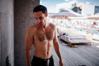 Delikanlı dışarıda duş alıyor. Güçlü kaslı ve güçlü bir adam su işlemleri yapıyor. Düşüyor. Vücudunu ve başını yıka. Dışarıda yalnız..