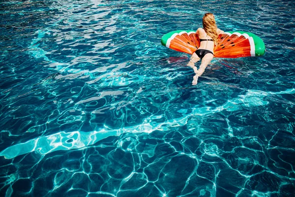 Молодая горячая женщина отдыхает в купальнике. Вид сзади картина расслабленной стройная женщина в черном купальнике лежал на плавательном кольце в воде и весело. Женщина купается одна в курортном спа-центре летом. — стоковое фото