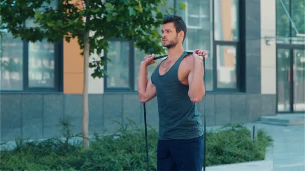 Mladý muž venku cvičí. Zpomalený pohyb sportovce zahřívá své silné tělo před tréninkem a tréninkem. Cvičení na ulici v městské budově.