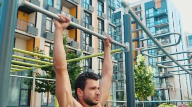 Genç adam dışarıda egzersiz yapıyor. Güçlü bir atletizm ustası güçlü ellerle egzersiz yapıyor. Başını yatay çizgide tut ve aşağı in. Daha iyi vücut şekli için eğitim egzersizi.