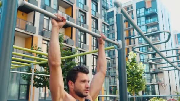 Un giovanotto che si allena fuori. Telecamera statica. Il tizio che fa esercizi di tiro con le braccia forti. Facendo attività di sport su strada a edificio. Atleta si prende cura della salute e bello. — Video Stock