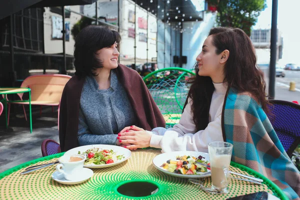 Mère mature et sa jeune fille s'assoient ensemble dans un café ou un restaurant. Les femmes avec de bonnes relations comme parler en famille et s'amuser pendant l'heure du déjeuner. Tenez-vous par la main avec amour. — Photo