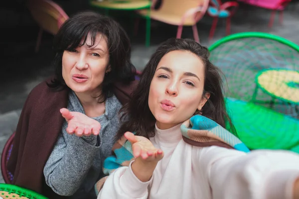 Mère mature et sa jeune fille s'assoient ensemble dans un café ou un restaurant. Selfie ou belles femmes différents âges. Envoyer des baisers à la caméra. Bonnes relations solides dans la famille. — Photo