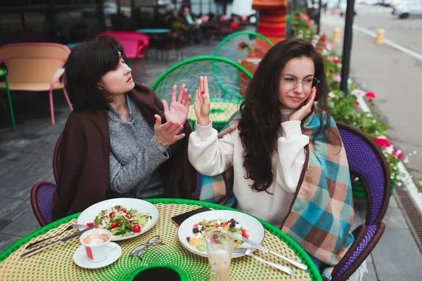 Mère mature et sa jeune fille s'assoient ensemble dans un café ou un restaurant. Un malentendu en famille. Fille et femme mûre ne sont pas d'accord. querelle entre mère et fille à l'extérieur au restaurant. — Photo