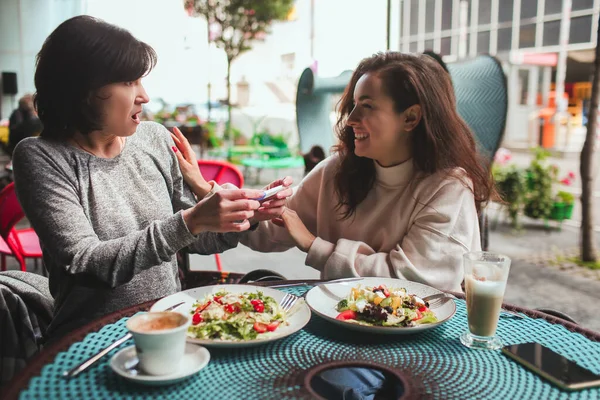Mère mature et sa jeune fille s'assoient ensemble dans un café ou un restaurant. Choqué femme mûre entendant parler de sa grossesse filles. Tous les deux heureux et joyeux. — Photo