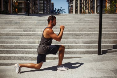 Genç adam dışarıda egzersiz yapıyor. Tek bacaklı atletizm sporcusunun önünde el ele tutuşması. Antrenman ya da egzersiz..
