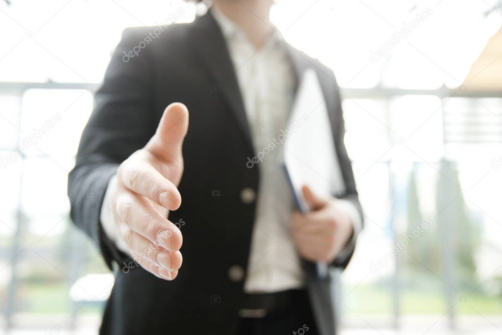 A businessman is stretching his hand at the camera. First person perspective