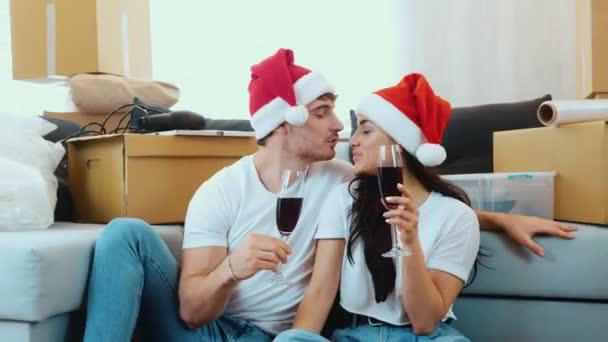 Genç çift yeni bir daireye taşınıyor. 2021 yılbaşı ya da Noel dönemi. Yeni bir dairede tatilleri kutlayan ve şarap içen bir çift. Birlikte vakit geçirin ve eğlenin.. — Stok video
