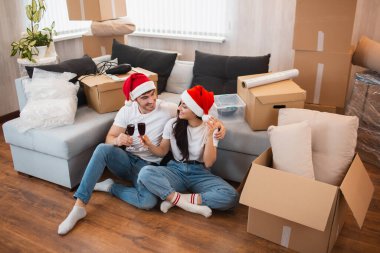 Yeni evli çift Noel 'i ya da yeni yılı yeni evlerinde kutluyor. Genç adam ve kadın şarap içiyor, yeni eve taşınmayı kutluyor ve kutuların arasında oturuyor..