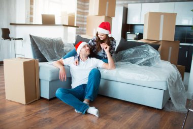 Yeni evli çift Noel 'i ya da yeni yılı yeni evlerinde kutluyor. Genç mutlu adam ve kadın yeni evine taşınıp kutuların arasında oturmayı kutluyorlar..