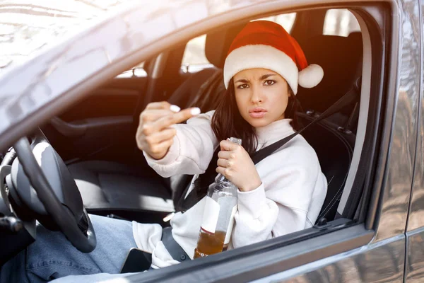 Fuck yourself Happy New Year and Merry Christmas An angry Drunk woman is sitting in a car, she is dressed in a red Santaclaus hat and shows the middle finger to the camera. Fuck yourself — стоковое фото