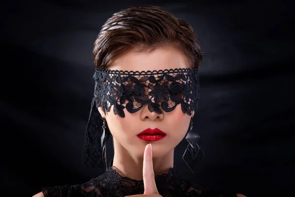 Close up head shot of Fashion Young tanned skin Asian Woman brown short hair beautiful cosmetic make up fashion tie black lace cover Eyes Face red lipstick. Studio Lighting dark curtain Background