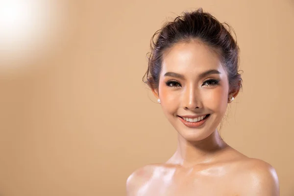 时尚亚洲女人的肖像湿油护肤有着美丽的发型 女孩笑着看了看米黄色的背景色 — 图库照片