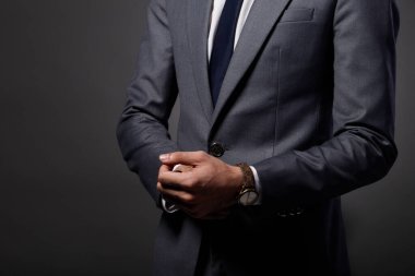 Yarım Vücut 20 'li yaşların Asyalı İş Adamı gri takım elbise kravat, stüdyo ışıklandırması koyu arka plan, bronzlaşmış cilt modeli yüz yok, bilek fotokopi alanı